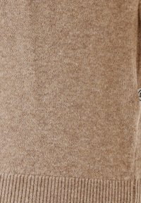 Tan knitted sweater featuring a soft texture, ribbed hem, and subtle flecks throughout the fabric. Standard fit with short sleeves.