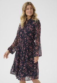 Navy floral dress with long sheer sleeves, button-down front, cinched waist, and layered ruffle hem featuring pink and green flower patterns.
