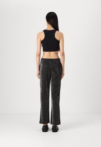 Top court noir à bretelles épaisses associé à un pantalon large noir brillant taille haute, doté d'une taille élastique et de poches arrière.