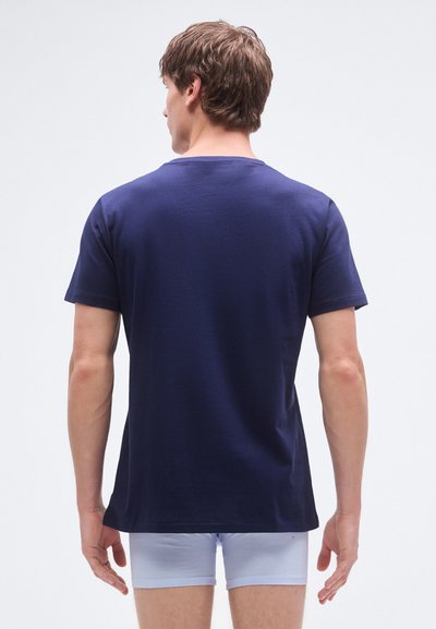 T-shirt azul-marinho de algodão, de mangas curtas, gola redonda, design simples, usado com boxers azul-claro, modelo de costas.