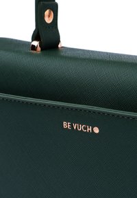 Grüne Handtasche mit texturierter Oberfläche und glatter Struktur, ausgestattet mit roségoldenen Akzenten und dem geprägt aufgedruckten Markennamen "BE VUCH" auf der Vorderseite.