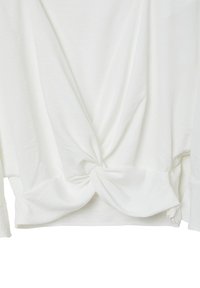 Camicia bianca a maniche lunghe con dettaglio a nodo twist in vita, caratterizzata da una texture morbida e liscia e una vestibilità morbida.