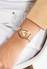 Orologio da polso in mesh color oro rosa con quadrante triangolare decorato con cristalli, dotato di indicatori delle ore minimalisti e di un bracciale metallico.