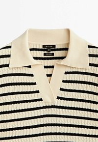 Pull polo à col en crème avec des rayures horizontales noires, présentant un motif tricoté texturé. Fabriqué en 100 % coton, avec un col en V.