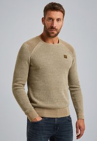 Beige gebreide trui van een textuurstof, met een ronde halslijn en geribbelde manchetten. Kenmerkt contrasterende schouderaccenten en een klein logo.
