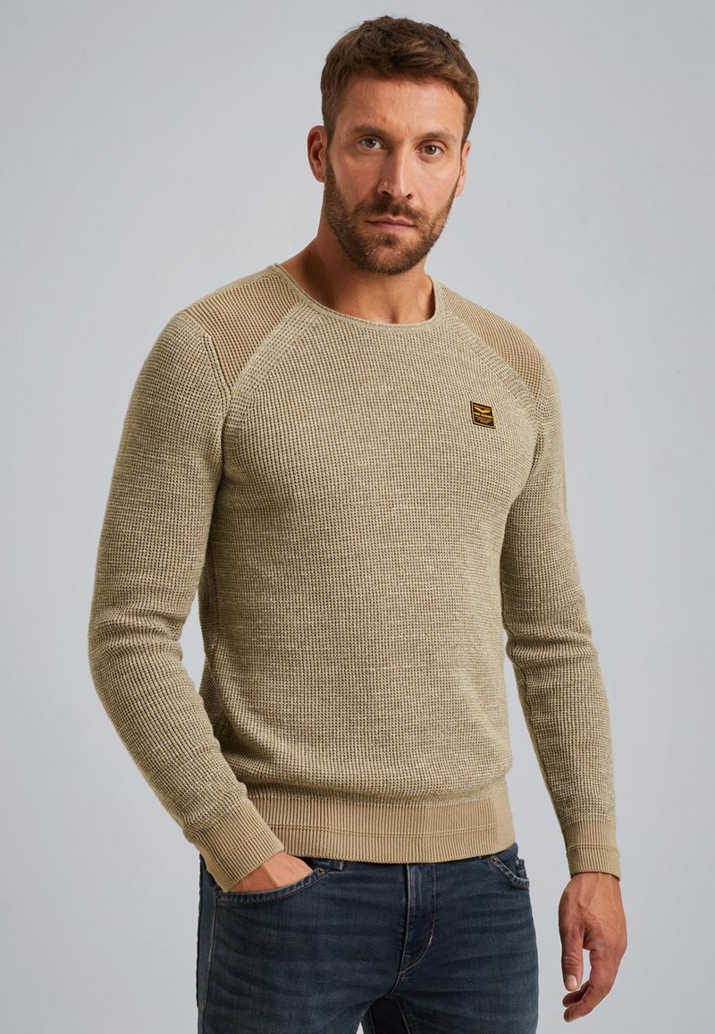 Beige gebreide trui van een textuurstof, met een ronde halslijn en geribbelde manchetten. Kenmerkt contrasterende schouderaccenten en een klein logo.