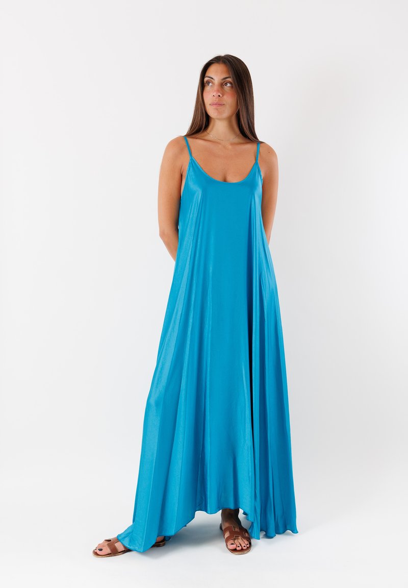 Vestito lungo senza maniche di colore blu, realizzato in un tessuto leggero e morbido. Presenta una vestibilità ampia con sottili spalline e arriva fino alle caviglie.