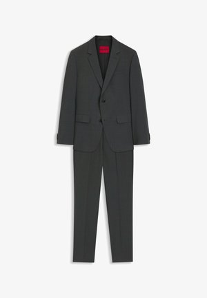 Costume homme deux pièces gris foncé avec blazer à revers crantés et pantalon assorti, avec une étiquette rouge « HUGO » à l’intérieur de la veste.