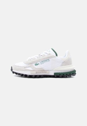 White and light gray Lacoste sneaker with green accents, textured sole, and logo text on side and tongue.