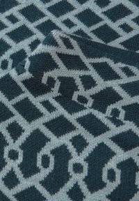 Tessuto con un motivo geometrico in turchese e azzurro chiaro. Il design include quadrati e rombi con una consistenza morbida.
