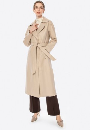 Trench coat beige in ecopelle, con ampio colletto, vita cintata e maniche lunghe. Dettagli di cucitura notevoli e tasche laterali.