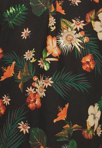 Tessuto floreale con fiori e foglie colorati in tonalità di arancione, verde e bianco su uno sfondo nero. Dettagli della superficie testurizzata visibili.