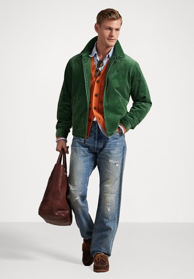 Giacca di velluto a coste verde, maglione arancione, camicia azzurro chiaro, jeans chiari strappati, borsa in pelle marrone e scarpe marroni.