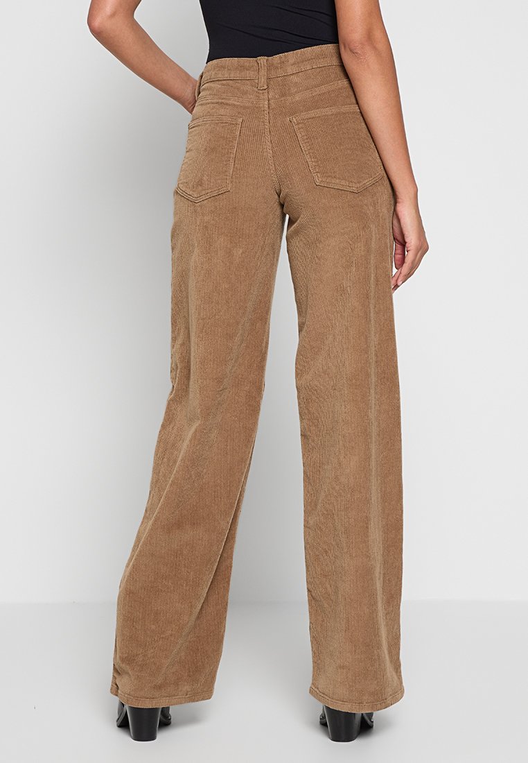 Pantaloni a gamba larga in corduroy di colore marrone con righe verticali, dotati di due tasche posteriori e un alto punto vita.