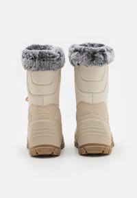 Une paire de bottes d'hiver beiges avec doublure en fausse fourrure grise, semelles robustes et tiges en tissu rembourrées, vues de l'arrière sur un fond blanc.