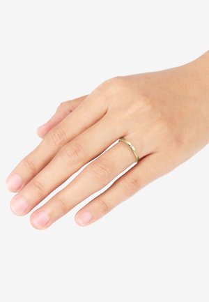 Goldring mit einem schlichten Banddesign, der einen kleinen, klaren Akzentstein enthält. Getragen an einer Hand mit leicht manikürten Fingern.
