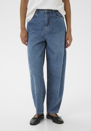 Jeans in denim azzurro chiaro con vita alta, vestibilità ampia e gambe dritte. Presentano una chiusura con bottone e tasche frontali. Indossati con ballerine nere.