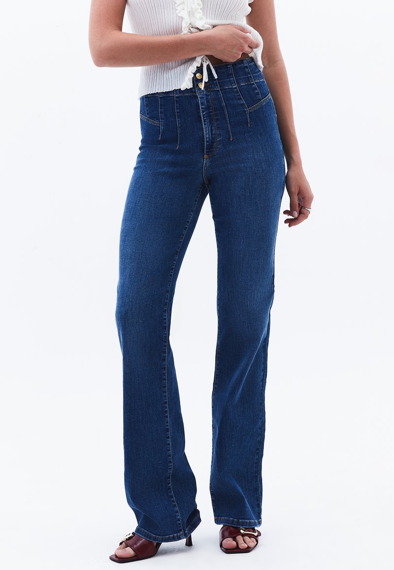 Högmidjade, utställda denimjeans i mörkblått, med en klassisk femficksdesign, sydda detaljer och knäppning med knappar.