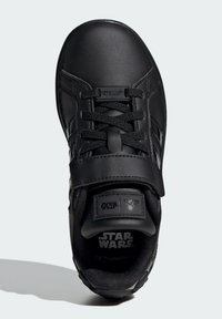 Black sneaker featuring a smooth leather upper, lace closure, strap, and "Star Wars" branding on the tongue and insole. Textured interior lining.