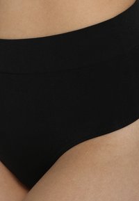 Des sous-vêtements noirs taille haute en tissu doux, dotés d'un design sans coutures et d'une ceinture extensible pour plus de confort.