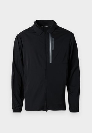Chaqueta ligera negra con cremallera frontal, cuello, puños elásticos y un bolsillo en el pecho con un acento reflectante. Textura suave y diseño informal.