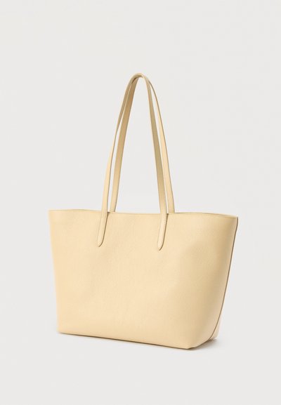 Δερμάτινη τσάντα ώμου σε ανοιχτό κίτρινο. Διαθέτει μακριές, επίπεδες λαβές, δομημένο σχήμα και υφιστάμενη επιφάνεια. Σχεδιασμός με ανοιχτό πάνω μέρος, χωρίς ορατά κλείστρα.