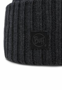 Knitted dark gray beanie hat with vertical ribbing, featuring a black fabric logo patch with circular design. Soft texture, casual fit.