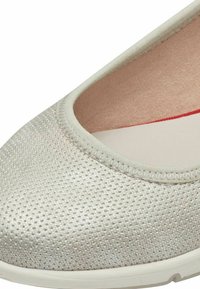 Ballerine en argent clair avec une surface texturée ; elle possède un bout arrondi et une doublure intérieure lisse en rose. Semelle blanche pour le confort.