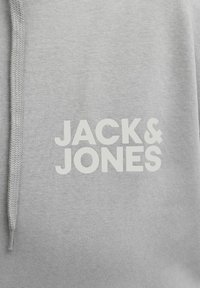Grauer Pullover aus weichem Baumwollgemisch mit weißem "JACK & JONES"-Logo. Strukturierter Stoff mit Kordelzug an der Kapuze.