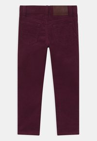 Bordové manšestrové kalhoty s rovnými nohavicemi, které mají dvě zadní kapsy a hnědou koženou nášivku s logem v pase.