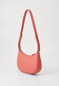 Bolsa de ombro em pele coral com formato curvo. Apresenta uma alça destacável com furos e um fecho de zip no topo. Textura suave, design minimalista.