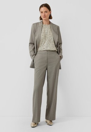 Costume gris à carreaux avec un blazer ajusté et un pantalon large, associé à un haut en sequins dorés scintillants et des chaussures métalliques. Pantalons texturés.