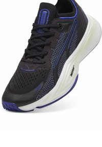 Fekete sportcipő lila részletekkel, hálós felsőrész és párnázott bokarész. Jellemzője a párnázott fehér középtalp és a texturált gumitalp.