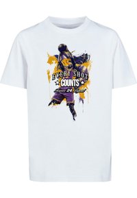 T-shirt en coton blanc avec un imprimé graphique coloré d'un joueur de basket, accompagné du texte "CHAQUE TIR COMPTE" en accents noirs et jaunes.