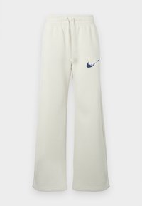 Krém színű pamut keverék melegítőnadrág, laza szabású, rugalmas derékpánttal és húzózsinórral, elöl egy sötétkék Nike logóval.