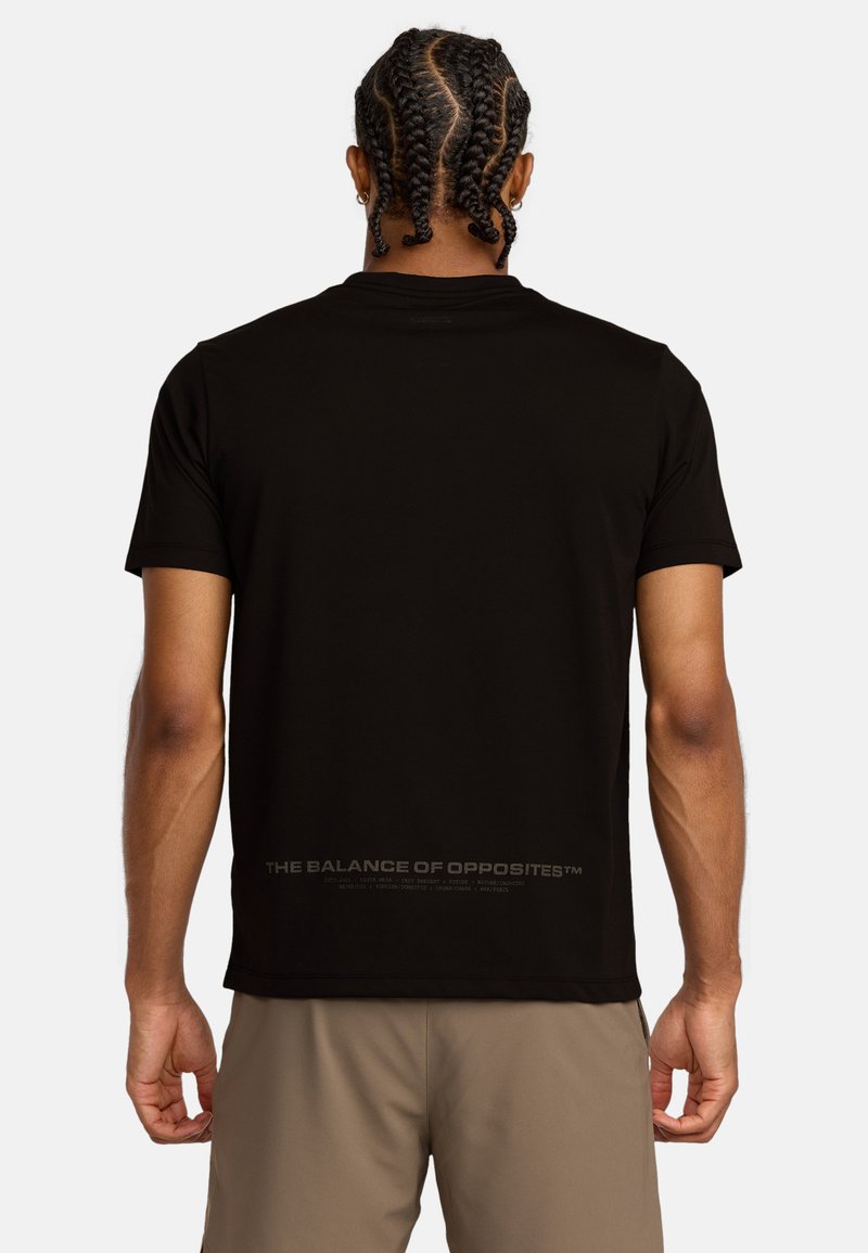 T-shirt nera a maniche corte con scollatura rotonda; presenta una stampa testuale lungo la parte bassa della schiena. Tessuto morbido con un design aderente.