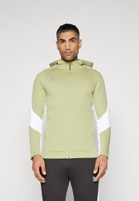 Lichtgroene rits-trui met witte zijkanten, capuchontoggles en een logo op de borst. Zachte stof met een aansluitend ontwerp.