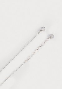 Collana in argento con una chiusura e lunghezza regolabile, caratterizzata da un piccolo dettaglio rotondo. Texture metallica liscia e design a maglie aperte.