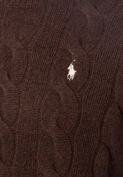 Pull en laine côtelée marron fait de laine épaisse avec un design texturé. Présente un petit logo brodé blanc sur la poitrine.