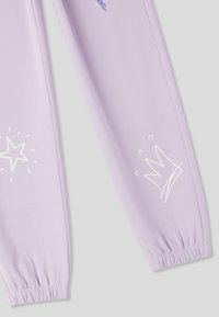 Pantaloni della tuta lilla con polsini elastici, con stampe grafiche bianche di una stella e una corona sulle gambe inferiori. Texture del tessuto morbida.