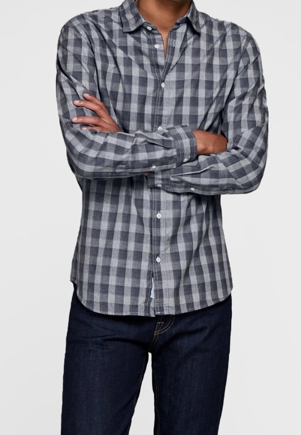Szara i czarna koszula w kratę zapinana na guziki, wykonana z materiału o miękkiej teksturze. Posiada długie rękawy i kołnierzyk, noszona z ciemnymi dżinsami.