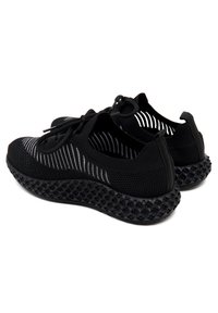 Schwarze Sportschuhe mit einem Obermaterial aus Mesh, das weiße Streifenakzente bietet. Die Sohle ist schwarz und strukturiert mit kreisförmigen Mustern und hat eine abgerundete Form.