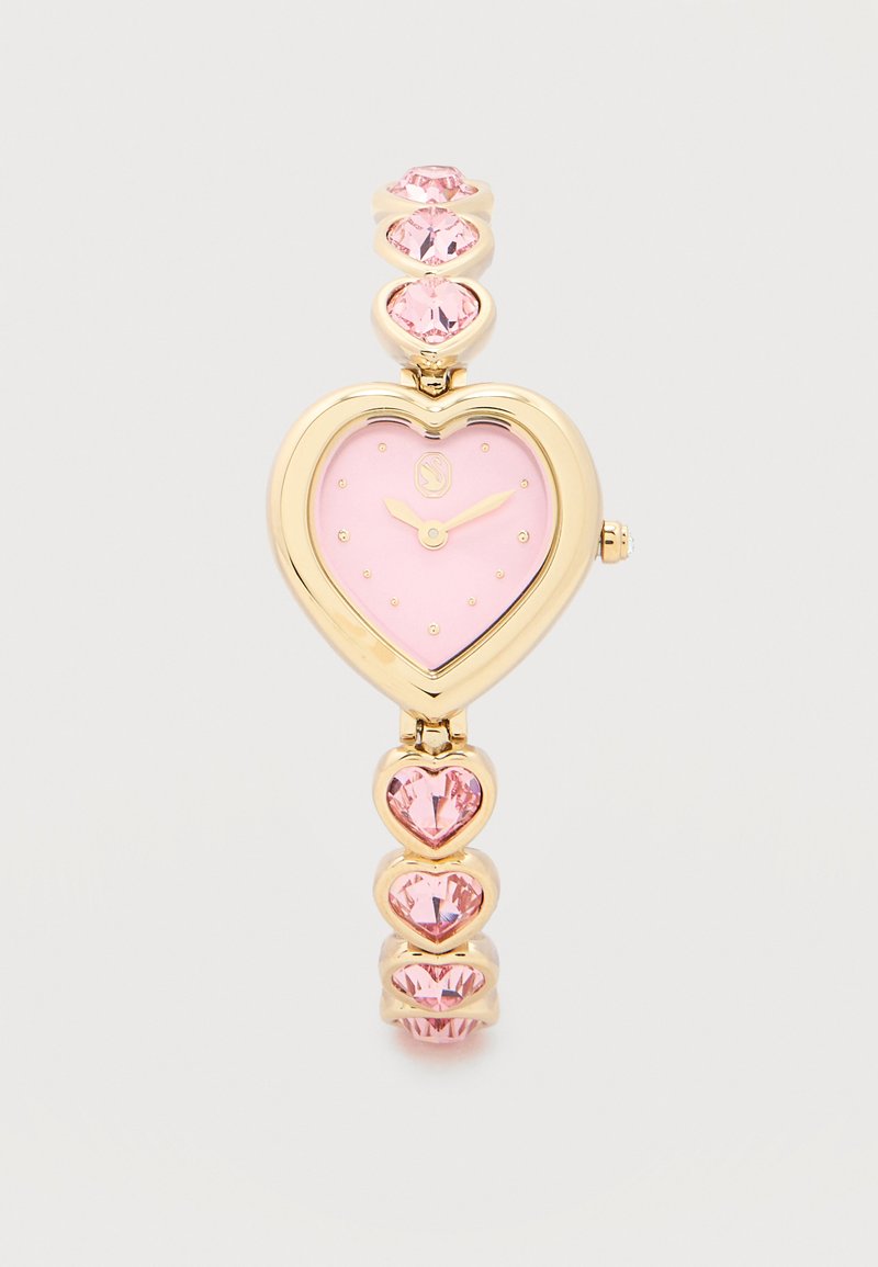 Reloj de pulsera de oro con una carátula rosa en forma de corazón y gemas rosas en forma de corazón en la correa, mostrando la hora 2:10.