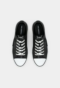 Μαύρα δερμάτινα αθλητικά παπούτσια με λευκά κορδόνια, λευκές μύτες και λογότυπο στη γλώσσα. Διαθέτουν ομαλή υφή και στρογγυλεμένο σχήμα.