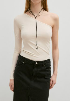 Beige geribbelde lange mouw top met één schouder bloot, gecombineerd met een hoge taille zwarte denimrok met voorzakken en een knoopsluiting.
