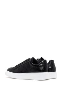 Par de zapatillas negras de corte bajo con textura de cocodrilo y suelas de caucho blancas, mostradas desde ángulos trasero y lateral sobre fondo blanco.