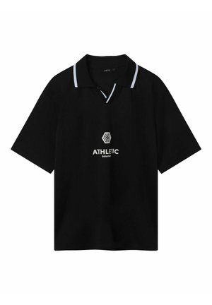 Camisa polo negra de manga corta con un cuello blanco en contraste y escote en V abierto, que presenta un logotipo y el texto "COMPORTAMIENTO ATLÉTICO" en el centro.