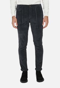 Pantaloni in corduroy grigio scuro con vestibilità ampia, dotati di una vita regolabile con cordoncino e orli arrotolati, abbinati a calzature nere.