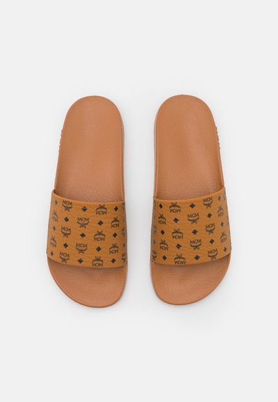 Des sandales marron avec une semelle texturée et une large sangle à motifs mettant en avant un design de logo en noir. Forme rectangulaire aux bords arrondis.