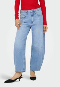 Ljusblå vida jeans med hög midja, framfickor och subtila slitningar, i kombination med svarta klackiga slingback-skor.